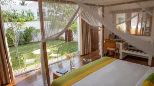 a bedroom with a bed and a large window at Calamansi Cove Villas in Balapitiya