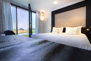 a bedroom with two beds and a large window at L'Agapa Hôtel - Spa Codage in Perros-Guirec