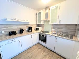 Dünenpark 053 في بينز: مطبخ بخزائن بيضاء ومغسلة