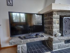 a large flat screen tv on a stone fireplace at Relax aux Paccots : été comme hiver in Les Paccots