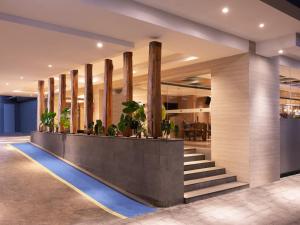 a lobby with a staircase and potted plants at Aveta Hotel Malioboro in Yogyakarta