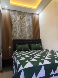 a bedroom with a bed with a green and white comforter at Justin Guest House in Jimbaran