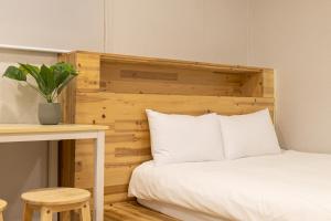 uma cama com uma cabeceira de madeira ao lado de uma mesa em Woody Two Bedroom In Hongdae em Seul