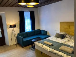 ein Schlafzimmer mit einem blauen Sofa und einem Bett in der Unterkunft Apartmán Gabriela in Červená Voda