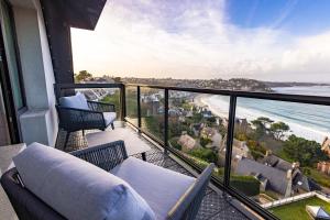a balcony with a couch and chairs and the ocean at L'Agapa Hôtel - Spa Codage in Perros-Guirec