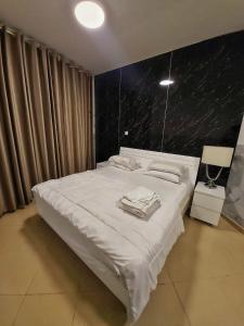 a bedroom with a white bed with a black wall at 1 BHK - Concorde Tower - JLT Cluster H in Dubai