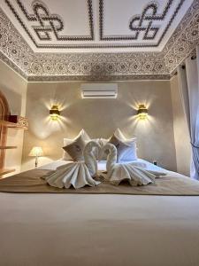 Dos cisnes hechos de almohadas en una cama en Riad Al Nubala, en Marrakech