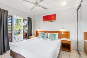 um quarto com uma cama grande e uma janela em Bay Village Tropical Retreat & Apartments em Cairns