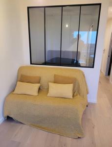 a couch with two pillows sitting in a room at Le Verdi - Les Gîtes de la Côte d'Amour in Le Croisic