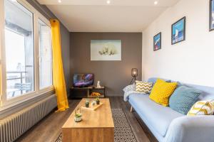 a living room with a blue couch and a table at Le COCON de Jaude F2 HyperCentre avec ascenseur 52Bonnabaud in Clermont-Ferrand