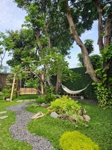 a garden with a hammock and a bench and trees at Roemah Uli Cirebon in Cirebon
