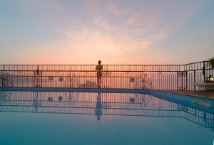 uma pessoa de pé sobre uma cerca ao lado de uma piscina em Daphovina Hotel em Nha Trang