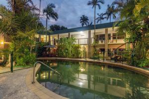 a hotel with a swimming pool in front of a building at Bay Village Tropical Retreat & Apartments in Cairns