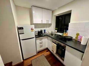 a kitchen with white cabinets and a white refrigerator at NY Special Granny Flat in Mosman in Sydney