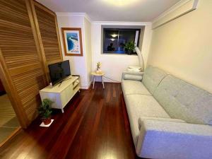 een woonkamer met een bank en een tv bij NY Special Granny Flat in Mosman in Sydney