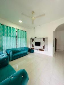 a living room with a blue couch and a tv at Noor Homestay Ira Jaya - 4 Home in Kangar