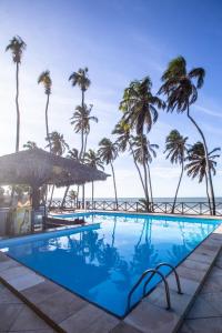 a swimming pool with palm trees and the ocean at Eco Paradise 110 - Cumbuco in Caucaia