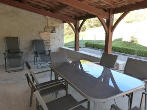ベルガンティにあるGîte avec Piscine proche de St Cirq Lapopieの屋根の下にテーブルと椅子付きのパティオ