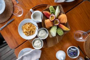 a wooden table with a plate of food and glasses of wine at Ekuthuleni Lodge in Welgevonden Game Reserve