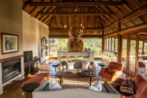 Ekuthuleni Lodge في محمية ويلغيفوندين غايم: غرفة معيشة مع أريكة ومدفأة