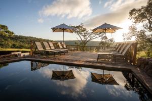 una terraza con sillas y sombrillas junto a una piscina en Ekuthuleni Lodge en Welgevonden Game Reserve