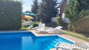 a swimming pool with white chairs and a swimming pool at HutiAgi apartman in Siófok