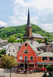 a red building with a clock tower and a church at FeWo.Mosel.barrierefrei+modern in Treis-Karden