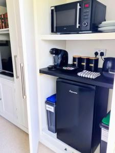 a kitchen with a black counter with a microwave at Luxury 4 poster lakefront rural retreat in Heckfield