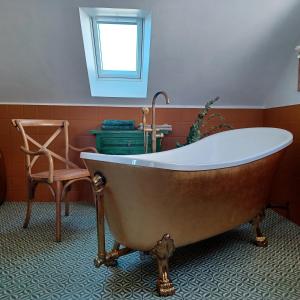 a bath tub in a bathroom with a chair at Le Banellou in Quimper