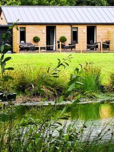 una baita di tronchi con un lago di fronte ad esso di Luxury 4 poster lakefront rural retreat a Heckfield