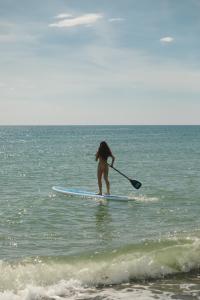 a woman standing on a paddle board in the ocean at The Nordic House in Bacnotan