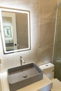 a bathroom with a sink and a mirror and a toilet at The Nordic House in Bacnotan