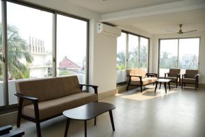 a living room with a couch and chairs and windows at Hotel Dolphin in Digha