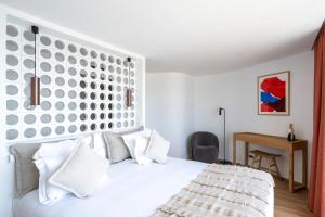 a bedroom with a white bed with a large headboard at Hôtel La Plage 5 étoiles La Grande Motte in La Grande Motte