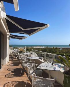 a row of tables and chairs with a view of the ocean at Hôtel La Plage 5 étoiles La Grande Motte in La Grande-Motte +65 photos
