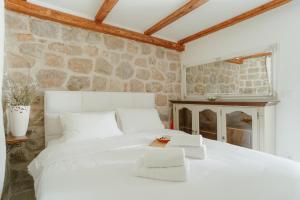 a bedroom with a white bed and a stone wall at Casa di Pietra in Kotor +19 photos