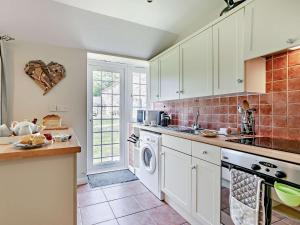 a kitchen with white cabinets and a washer and dryer at 2 Bed in Perranporth WHHOU in Perranporth