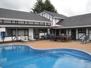 a swimming pool in front of a house at Devonwood Motel in Rotorua