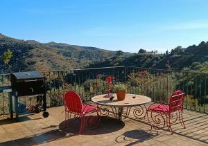 un patio con mesa, 2 sillas y parrilla en Beautiful House with Sea View and Nature, 30 minutes from Malaga, en Moclinejo