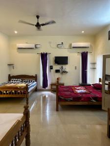 a room with two beds and a flat screen tv at Blissful Haven Art House - near entrance to Auroville in Auroville