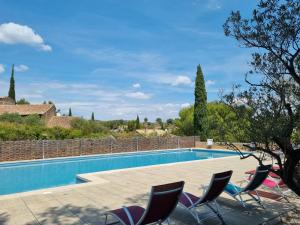 a villa with a swimming pool and two chairs at Les Garrigues de la Vall&eacute;e des Baux in Paradou