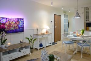 uma sala de estar com uma mesa e uma televisão na parede em Maya's Flats & Resorts 56 - Szafarnia em Gdansk