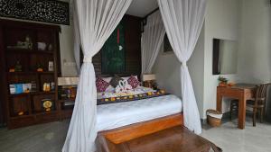 a bedroom with a bed with curtains and a desk at Ubud Paradise Villa in Ubud