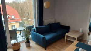 ein blaues Sofa im Wohnzimmer mit Fenster in der Unterkunft Apartament Alicja in Międzywodzie