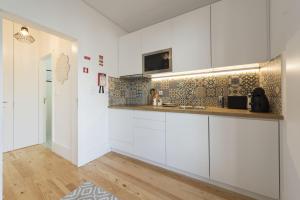 eine Küche mit weißen Schränken und einem TV an der Wand in der Unterkunft S. Bento Downtown Apt in Porto
