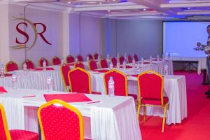 une salle de conférence avec des tables blanches et des chaises rouges dans l'établissement Selella Resort, à Kisumu