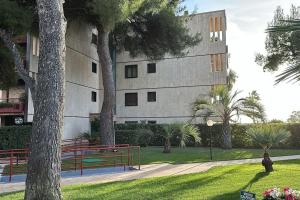 ein Gebäude mit Bäumen und Bänken in einem Park in der Unterkunft Sea Residence Porto Sole Vista Mare Con Posto Auto e Piscina in Sanremo