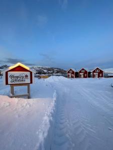 een bord in de sneeuw met huizen op de achtergrond bij Vengsøy Rorbuer in Vengsøya
