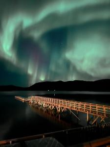 een houten brug in het water onder het noorderlicht bij Vengsøy Rorbuer in Vengsøya