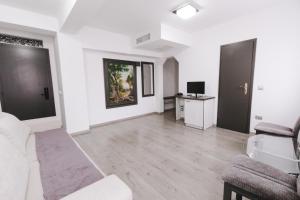 a white living room with a couch and a tv at Hotel Apollo Central in Sibiu